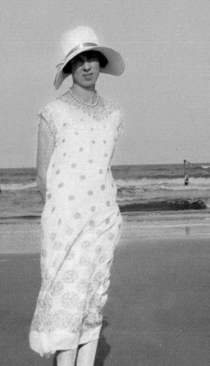 Elsie Stephens in white dress standing on beach, 1920s.
